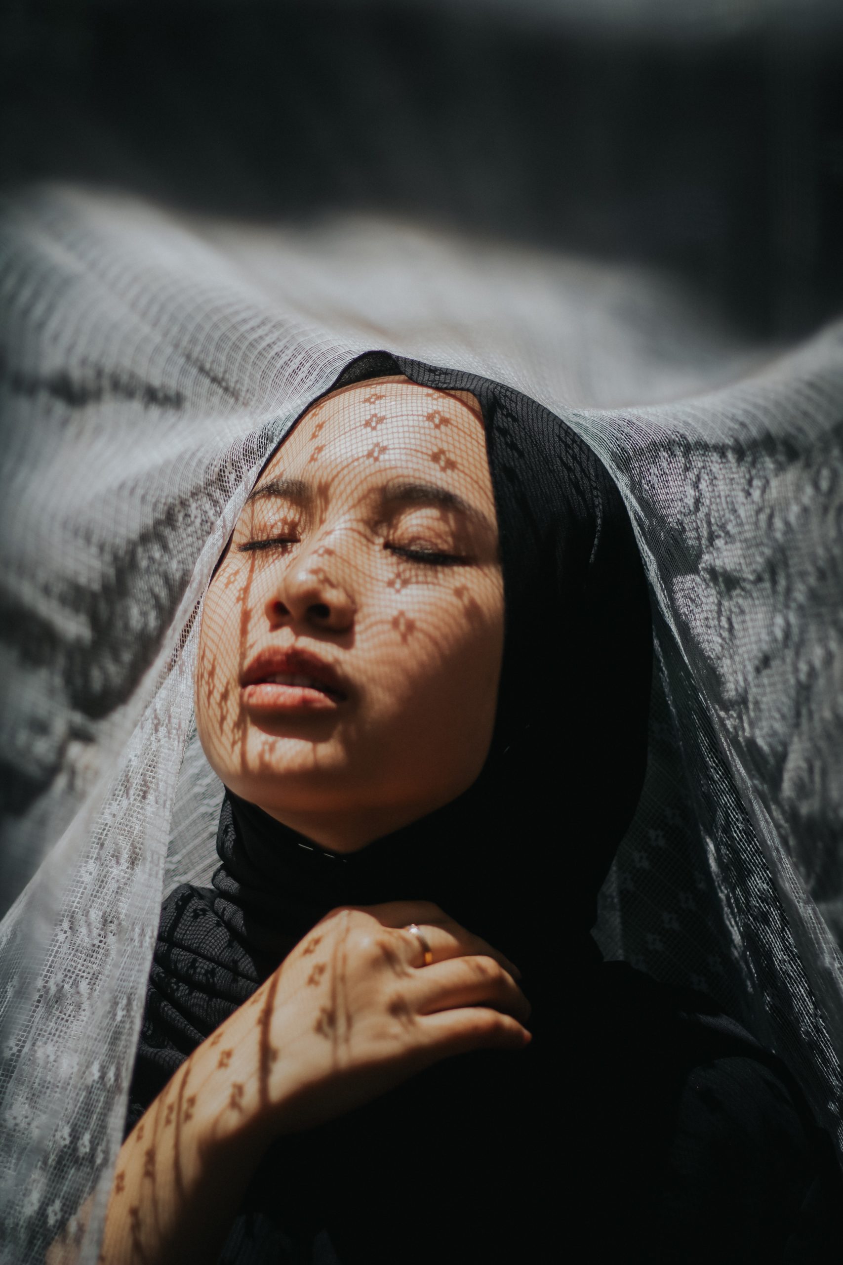 Woman Wearing Black Head Scarf in Grief Eyes closed as if in prayer