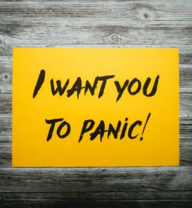 A yellow I want you to panic! sign on wooden background.